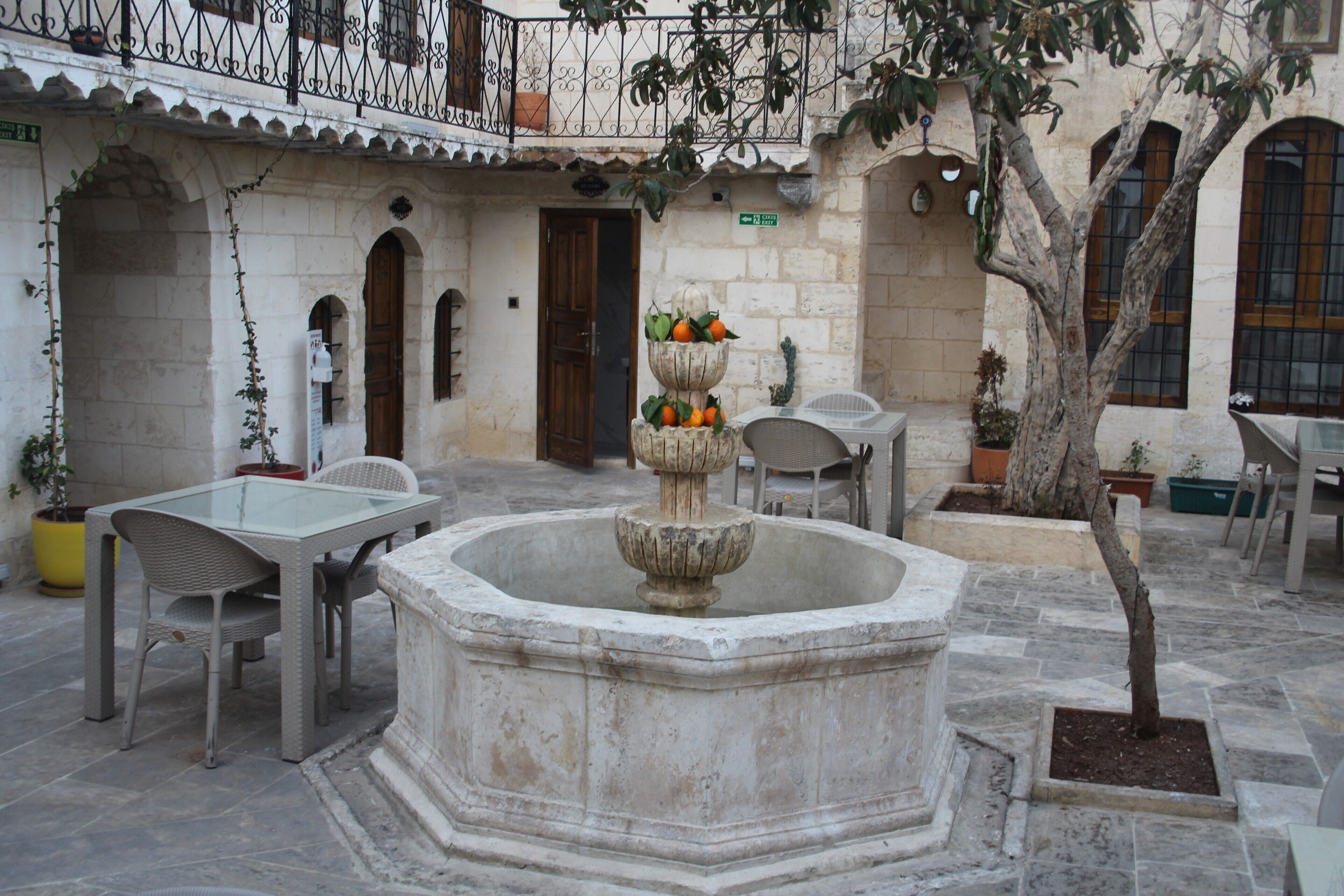 Un patio con una fuente central, bancos de piedra y plantas en macetas.