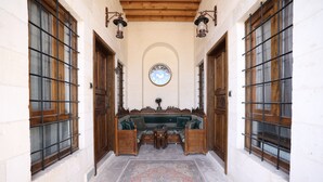 A corridor with a wooden bench, a patterned rug, and a wall clock. - Tessera Hotel (Sanliurfa)
