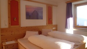 Una cama doble con cabecera de madera, una mesita de noche y una lámpara de pared.