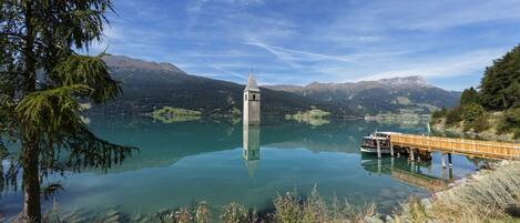 Un lago sereno con un puente de madera y una torre en el centro.