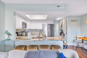 A modern kitchen with white cabinets, a central island, and a dining area with a table and chairs.