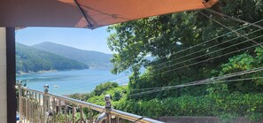 A balcony with a view of a lake and mountains. - Beach Getaway (Suite 201) for 1 - 3 guests: Perfect Location & Great Views. (Geoje-si)
