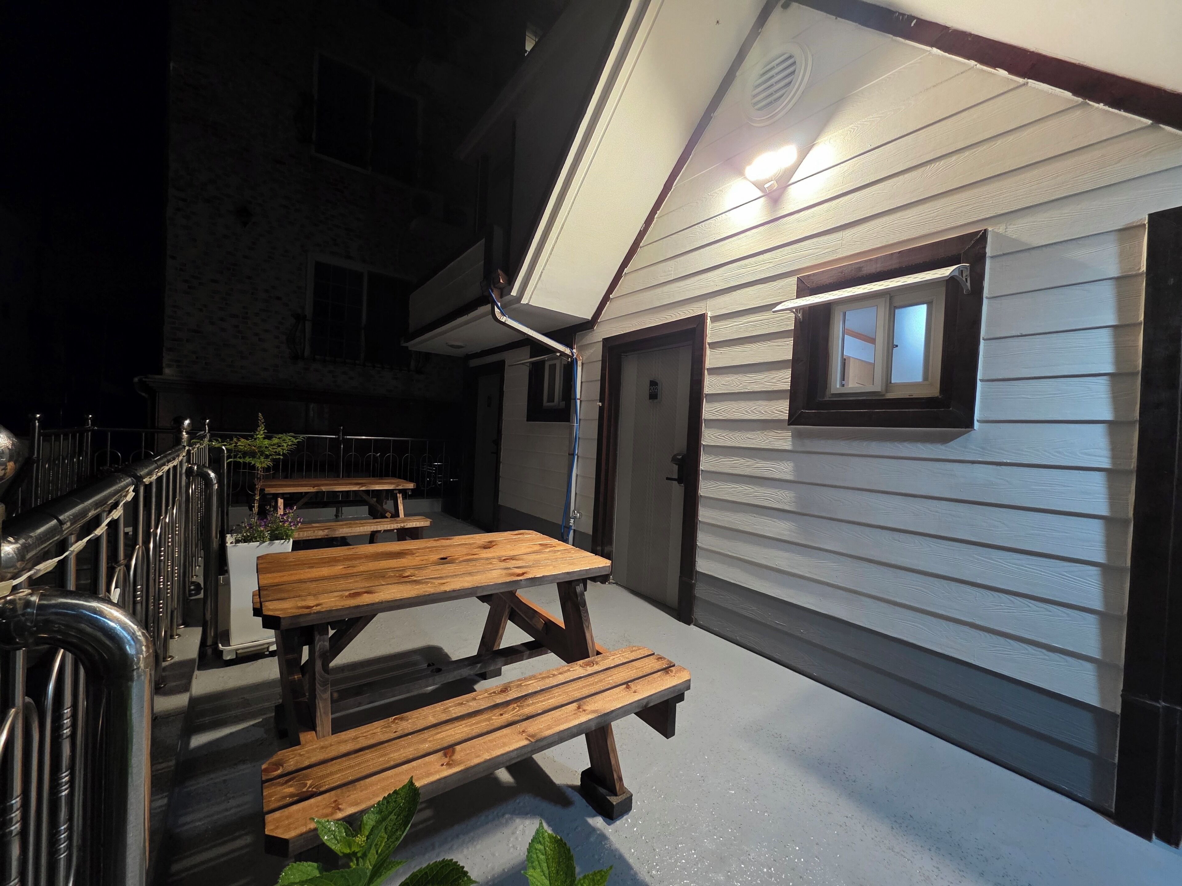An outdoor patio area with wooden benches and a metal railing.