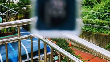 Blick von einem Balkon mit Geländer auf ein Gewässer und viel Grün.