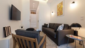 A modern living room with a sofa, a coffee table, a TV, and a bookshelf.