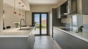 Una cocina moderna con una isla central, electrodomésticos de acero inoxidable e iluminación colgante.