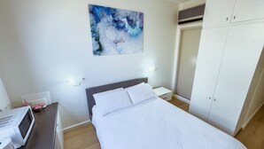 A bedroom with a bed, a nightstand, a microwave, and a wardrobe. - City Studio | Netflix Premium 4K | 65" LG QLED TV | Queen Memory Foam Bed (Adelaide)