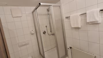 Ein Badezimmer mit Duschkabine, Toilette und Handtuchhalter.