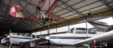 A hangar with multiple small aircraft parked inside.