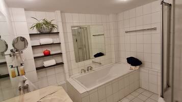 Un baño moderno con una bañera grande, zona de ducha y tocador con espejo y lavamanos.