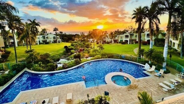 A swimming pool with lounge chairs and a sunset view. - Palms at Wailea #803 Fully Renovated, Partial Ocean View! Free Wifi, Full A/C (Wailea)