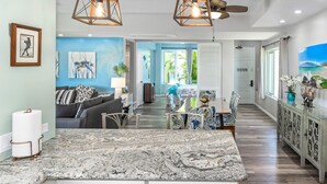 A spacious living area with a large kitchen island, a dining table, and a seating area with a sofa and chairs. - Palms at Wailea #803 Fully Renovated, Partial Ocean View! Free Wifi, Full A/C (Wailea)