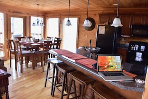 Un interno in legno con angolo cottura, tavolo da pranzo, sgabelli da bar e un portatile sul bancone.
