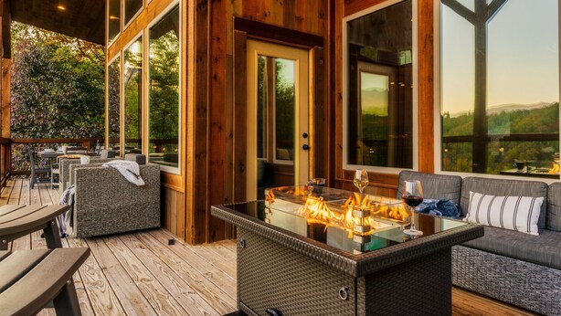 Eine Terrasse im Freien mit einem Tisch aus Glas, Sitzgelegenheiten und einem Feuerkorb.