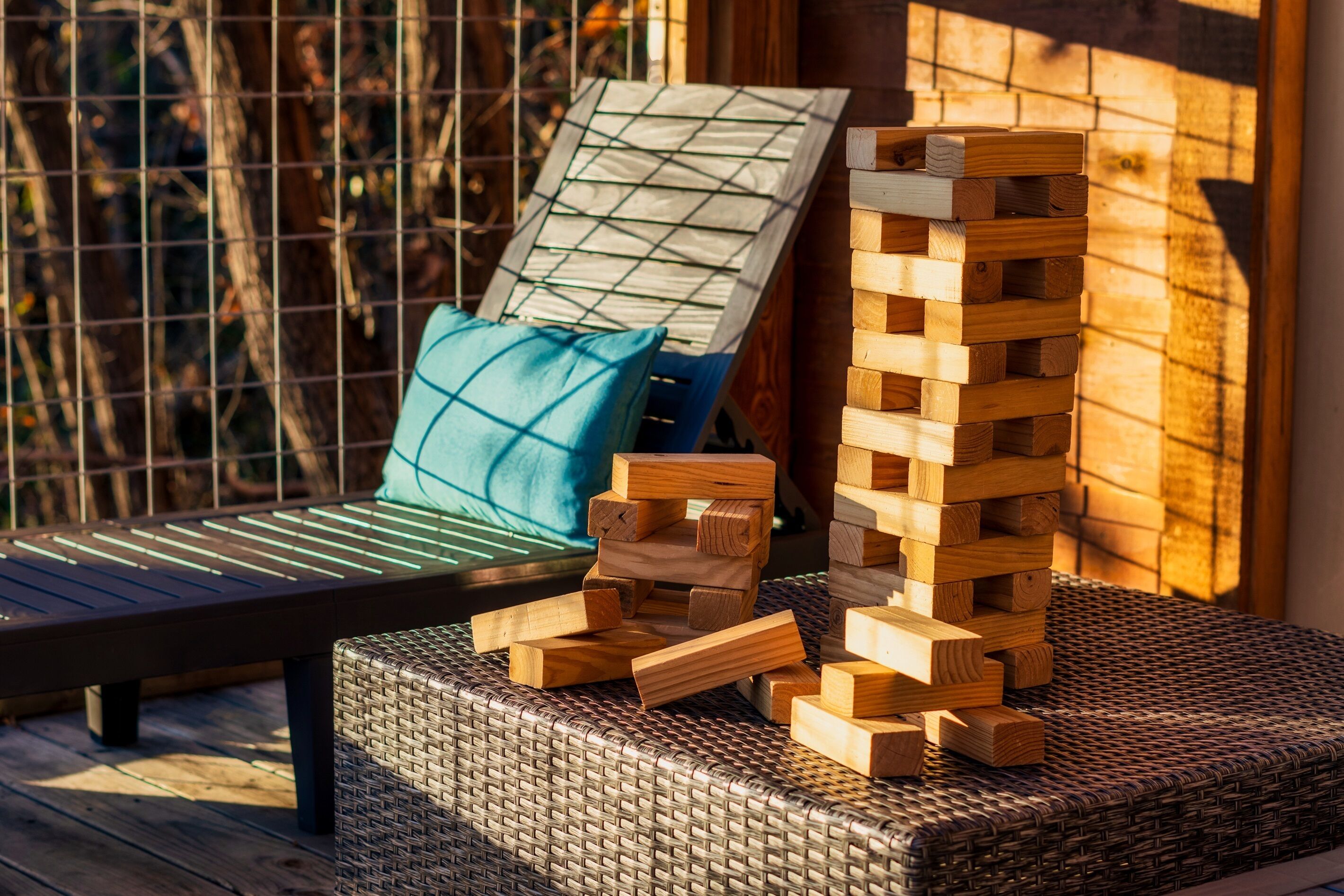 Una silla de mimbre con cojín, una torre de bloques de madera y un banco de madera.