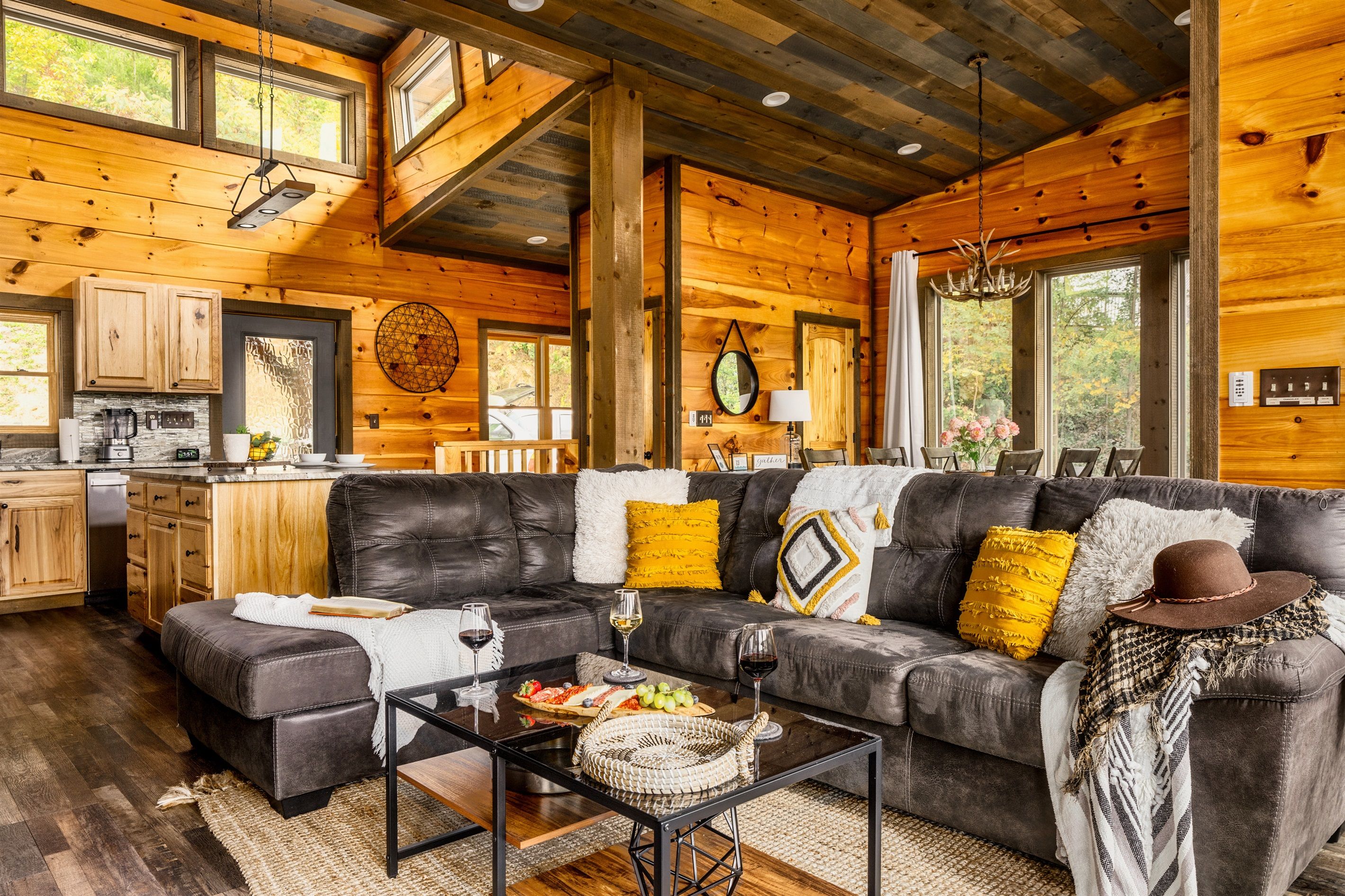 Ein gemütliches Blockhaus-Interieur mit Wohnbereich, der ein Ledersofa, einen Couchtisch und eine Küchenzeile mit Holzschränken und einer Arbeitsplatte umfasst.