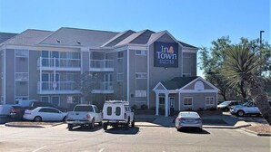 A multi-story hotel with a sign reading "In Town Suites". There are several cars parked in front, and a small building attached to the main structure. - Intown Suites Extended Stay El Paso Tx (El Paso)