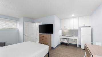 Une chambre d’hôtel moderne équipée d’un lit, d’un bureau, d’une télévision, d’un four à micro-ondes et d’un réfrigérateur.