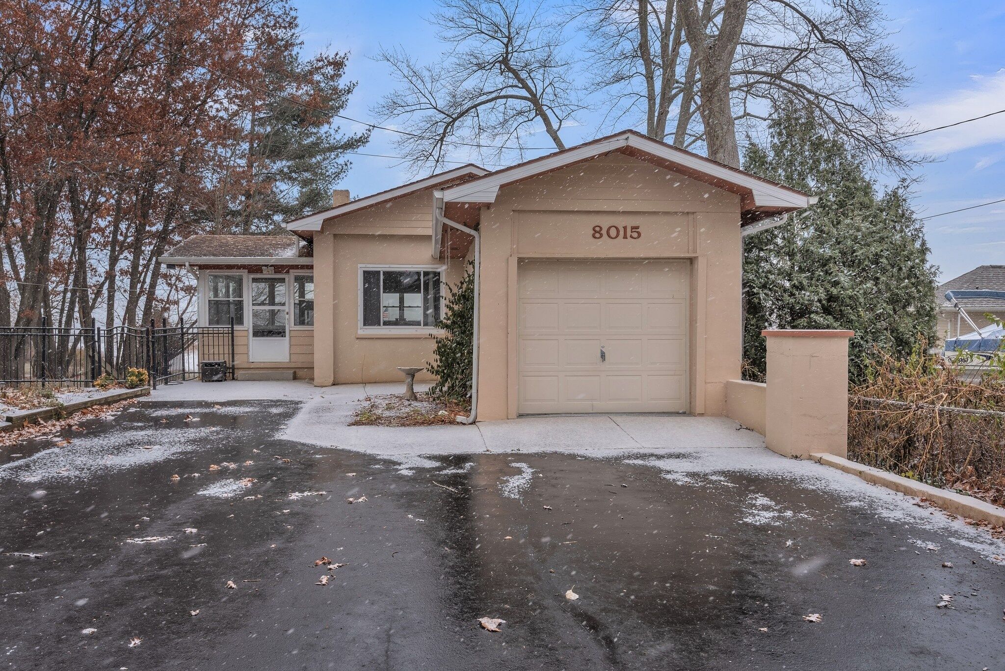 Ein zweigeschossiges Haus mit Garage, Hausnummer 8015, einem Vorgarten mit kleinem Garten und einer verschneiten Auffahrt.