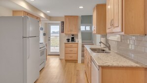 A kitchen with wooden cabinets, a white refrigerator, a sink, and a countertop.