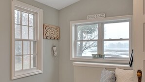 A room with a large window, a bench with cushions, a decorative wall piece, and a sign above the window reading "LONG LAKE".