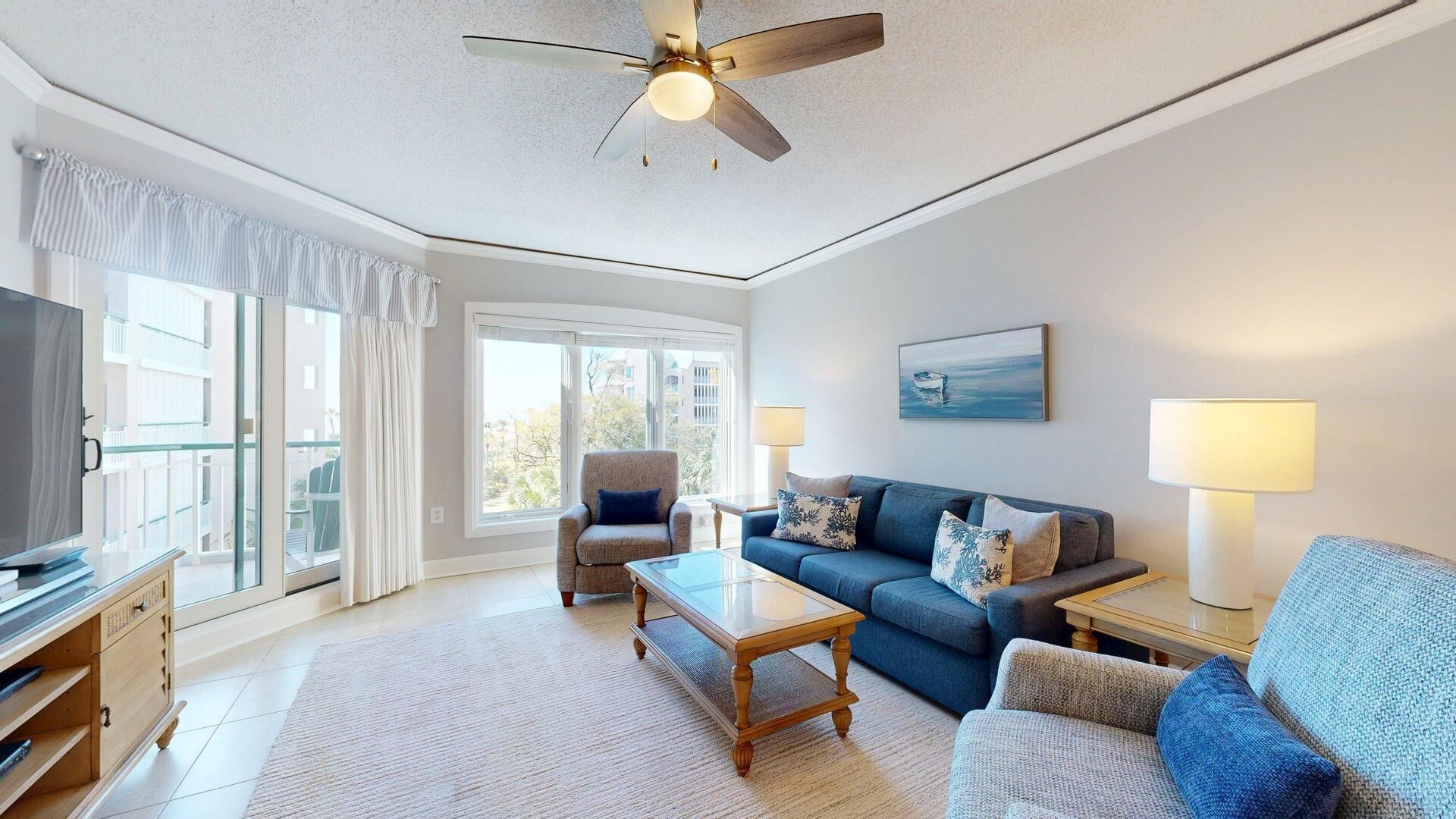 A modern living room with a ceiling fan, a sofa, a coffee table, and a TV.