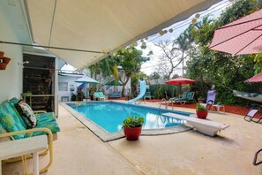 Ein Poolbereich mit Liegestühlen, Sonnenschirmen und Topfpflanzen.