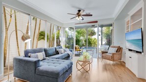 A spacious living room with a large sectional sofa, a coffee table, and a TV on a cabinet. - ISLAND OASIS ~ Stylish 2 Bedroom, 2 Bath Home w/ Private Heated Pool! (Key West)