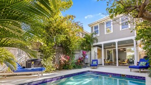 A backyard with a swimming pool, lounge chairs, and a covered patio area. - ISLAND OASIS ~ Stylish 2 Bedroom, 2 Bath Home w/ Private Heated Pool! (Key West)