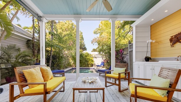 A covered outdoor patio with wooden furniture and a view of a swimming pool. - ISLAND OASIS ~ Stylish 2 Bedroom, 2 Bath Home w/ Private Heated Pool! (Key West)