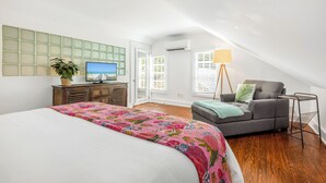A bedroom with a bed, a gray sofa, a TV, a plant, and a lamp. - BAHAMA DREAMING ~ Incredibly Located 3 Bed, 2 Bath w/ Private Heated Pool! (Key West)