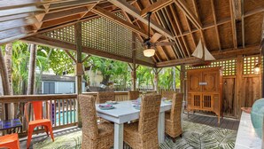 An outdoor dining area with wicker chairs, a table, and a pool in the background. - BAHAMA DREAMING ~ Incredibly Located 3 Bed, 2 Bath w/ Private Heated Pool! (Key West)