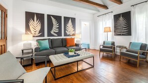 A living room with a sofa, two armchairs, a coffee table, and artwork on the wall. - BAHAMA DREAMING ~ Incredibly Located 3 Bed, 2 Bath w/ Private Heated Pool! (Key West)