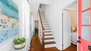 A staircase with wooden steps and a white door with a red frame leading to a bedroom. - BAHAMA DREAMING ~ Incredibly Located 3 Bed, 2 Bath w/ Private Heated Pool! (Key West)
