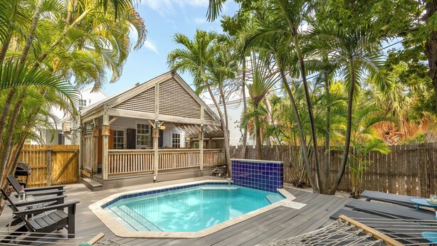 A backyard with a swimming pool, wooden deck, lounge chairs, and a wooden house. - BAHAMA DREAMING ~ Incredibly Located 3 Bed, 2 Bath w/ Private Heated Pool! (Key West)