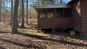 A rustic cabin with a wooden exterior, surrounded by a forest. - Fenced for your fur babies! 2 cabins on property for 1 price! (Mena)