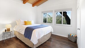 Una camera da letto con un letto grande, un comodino con una lampada e una finestra vista alberi.