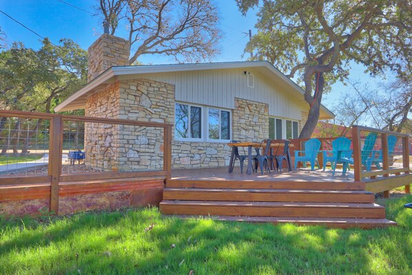 A house with a stone exterior, a wooden deck, and outdoor seating.