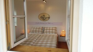 A small bedroom with a bed, a window, a wall-mounted picture, and a bedside table with a lamp. - Dream vacation apartment in an elevated position with unobstructed views (Lenggries)
