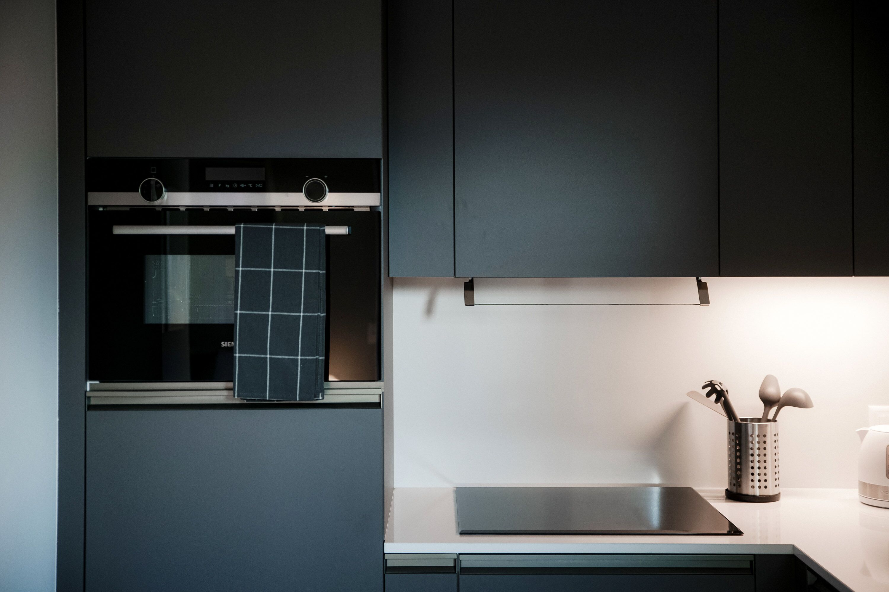 Eine moderne Küche mit Backofen, Edelstahl-Arbeitsplatte und Wasserkocher.