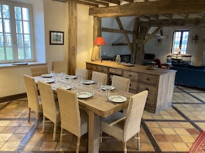 Een eetruimte met een houten tafel voor zes personen, omringd door rieten stoelen.