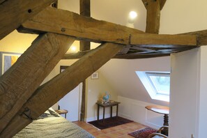 A room with exposed wooden beams, a skylight, a small table with a globe, and a patterned rug.