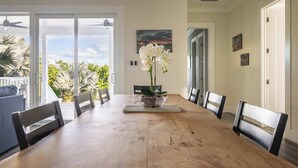 Un comedor con una mesa de madera, sillas y un centro de mesa con una orquídea en maceta.
