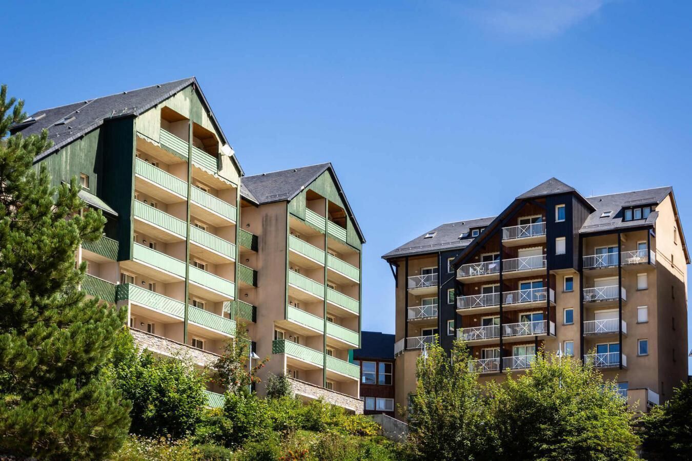 A multi-story hotel with balconies, surrounded by greenery.