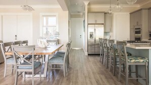 A modern kitchen with stainless steel appliances, a wooden dining table with chairs, and pendant lighting. - Waterlane House at Lunara Bay (Key West)