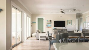 A spacious living room with a large TV, a dining area, and a kitchen. - Waterlane House at Lunara Bay (Key West)