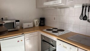 A compact kitchen with a microwave, toaster, coffee maker, and a stove. - 4th floor, jacuzzi, hammam, tv, ski locker, 40m², Peyragudes (Germ)
