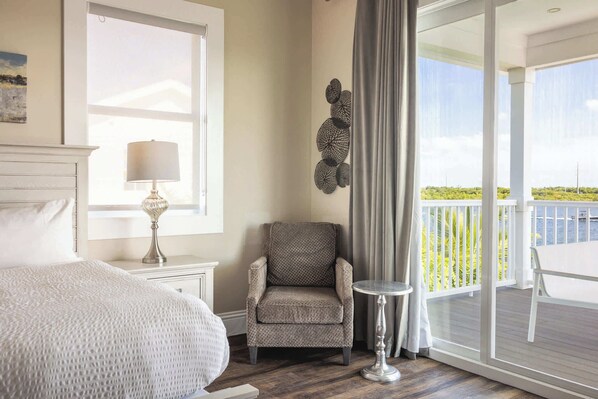 Une chambre à coucher avec un lit, une chaise, une petite table et une vue sur l’extérieur.