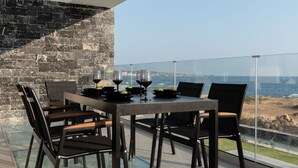 Un comedor moderno con una mesa y sillas de vidrio, con vistas al mar.