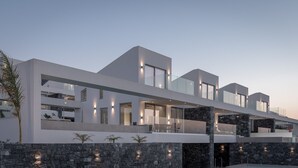 Un edificio moderno de varios pisos con amplias ventanas, fachada de piedra y zonas de estar al aire libre.